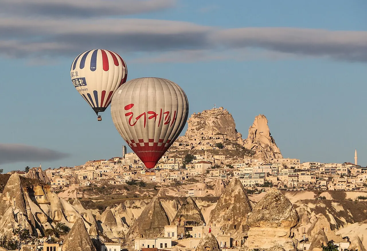 Two balloons beside the rock citadel of Uçhisar, Cappadocia