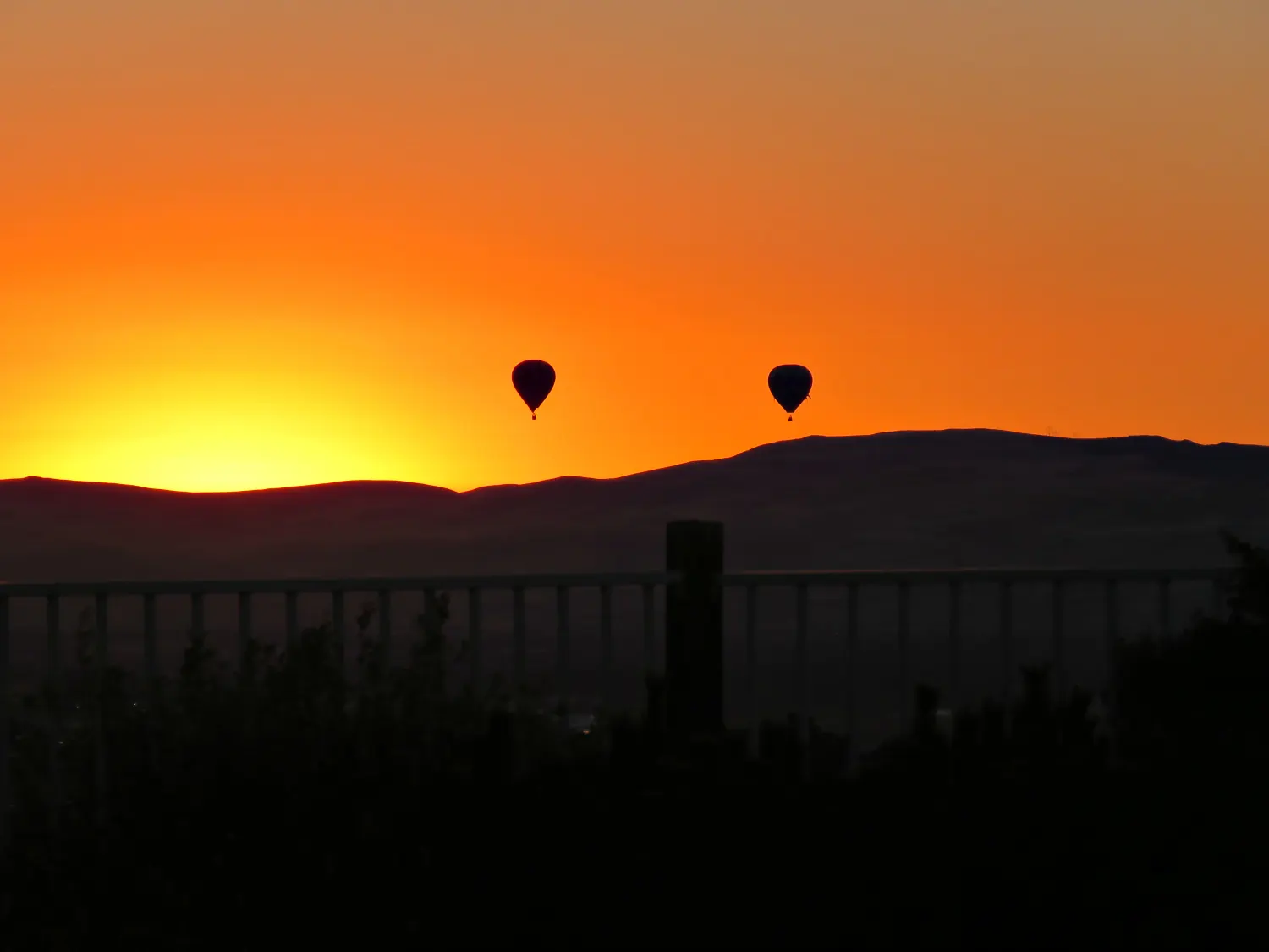 Two balloons silhouetted at sunrise during the Great Reno Balloon Race