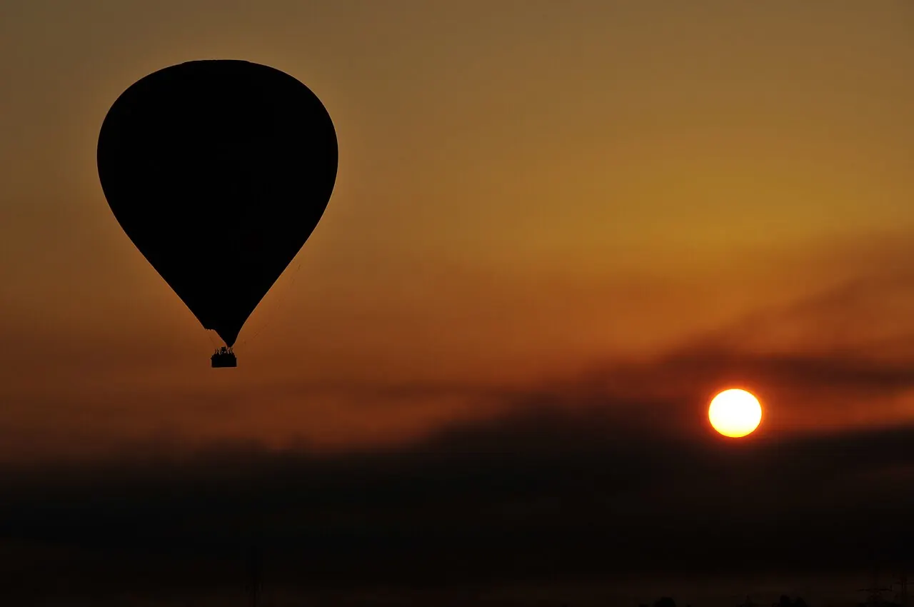 A hot air balloon silhouetted against the sunrise over Luxor